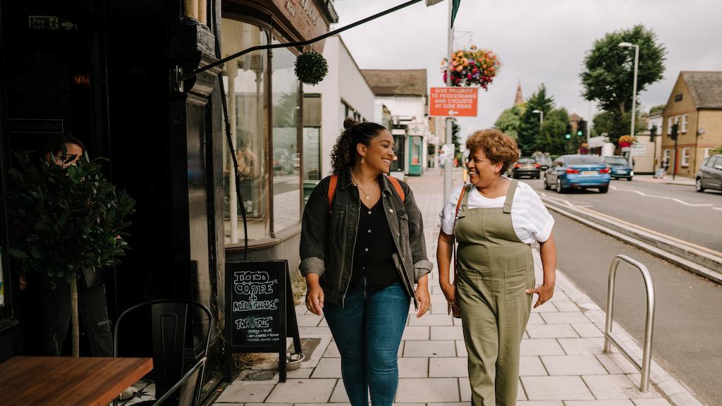 A younger woman and an older woman walk down a high street together
